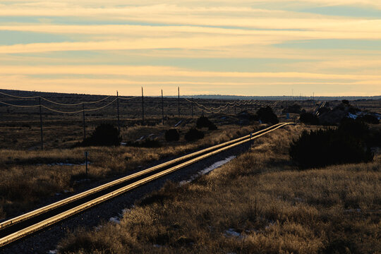 Train tracks receding into the distance diagonally at sunset