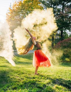Young dancer spinning with colorful powder exploding around her