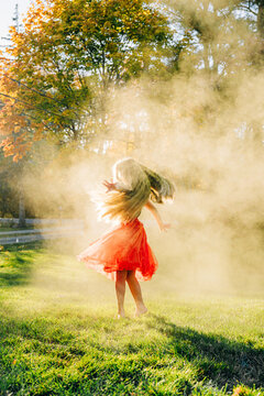 Young girl dancing in smoke bomb cloud in autumnal park