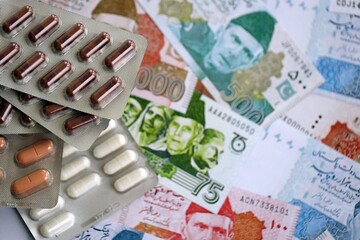 Pakistan rupees banknotes and medicine pills. Pakistan money bills with drugs close up