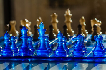 A vibrant chessboard scene featuring translucent blue and golden chess pieces