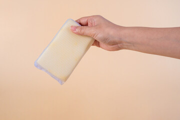 Brush household, cleaning sponge for cleaning and hand on cream background. 