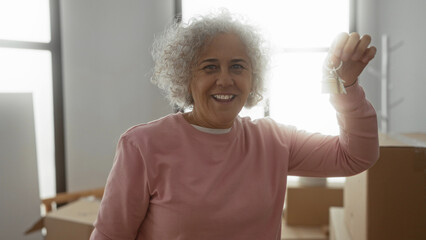 Woman celebrating keys to new home with joy in bright living room surrounded by moving boxes