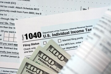 Hundred dollar bills and 1040 individual income tax return form blank close up