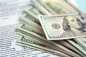 Big amount of United States dollar bills on table with 1040 tax return form