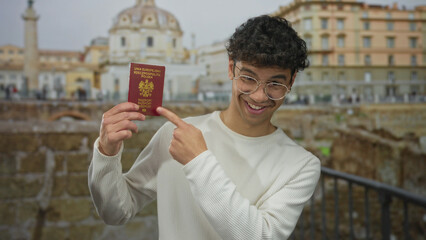 Man wearing white sweater holding passport and pointing finger at it at roman building; travel adventure.