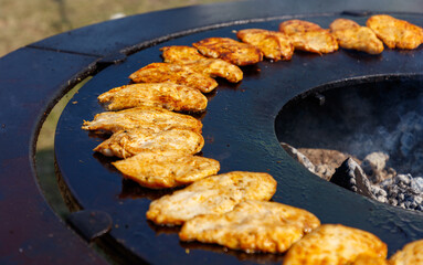 A large number of chicken wings are being cooked on a grill