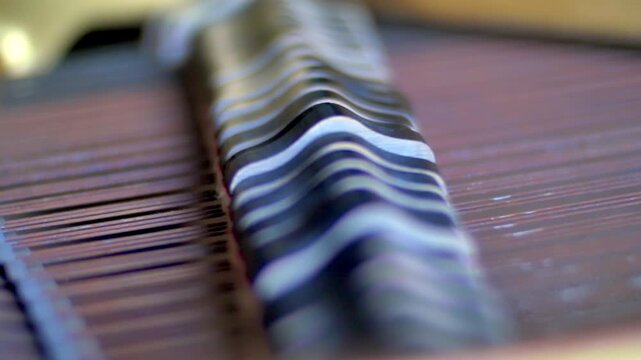 Close-up of piano strings with shallow focus creating rhythmic wave patterns and metallic shine