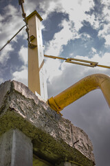 Industrial structure rises against a dramatic sky, showcasing rusting pipes and textured concrete...
