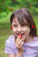 Young girl tasting cherries in a lush green garden setting