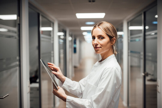 Medical professional in laboratory corridor using tablet for research