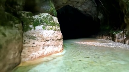 Serene turquoise waters flowing through a lush green cave, with shadows deepening in the background