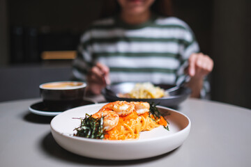 Closeup image of a woman eating spaghetti on dining table