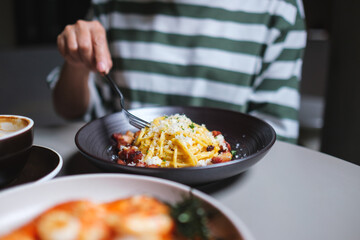 Closeup image of a woman eating spaghetti on dining table