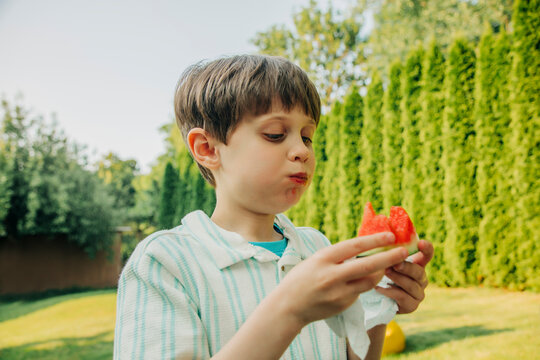 Child eating watermelon outdoors during summer vacation in backyard