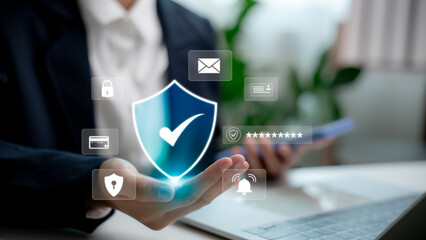 Businessperson holding virtual shield icon with cyber security and privacy symbols. Concept of...