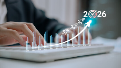 Hands typing on keyboard with growth chart and rocket icons aiming at 2026 target. Concept of business development, success strategy, annual performance tracking, and goal planning for the future.