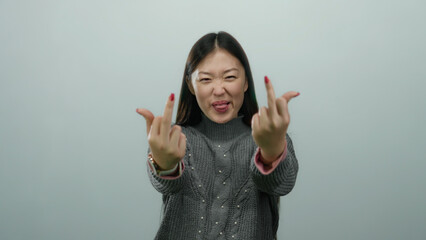 Woman making rude gesture with both hands on white background expressing defiance and attitude with playful expression in casual attire.