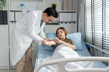 Asian male doctor examine patient woman lying on bed in recovery room. 