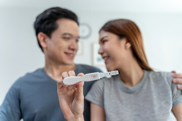 Asian young couple feeling happy after look at positive pregnancy test. 