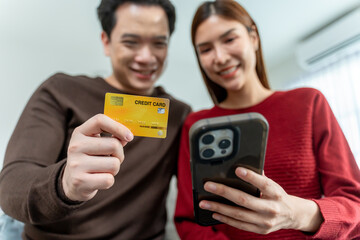Asian couple using smartphone shopping online in living room at home. 
