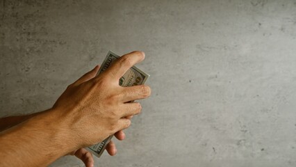 Man holding united states dollars against concrete background, illustrating finance, wealth, and...