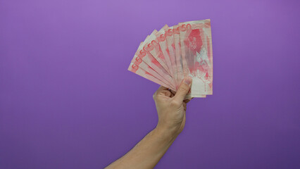 Hand holding philippine banknotes with a purple background showcasing money concept, featuring a...