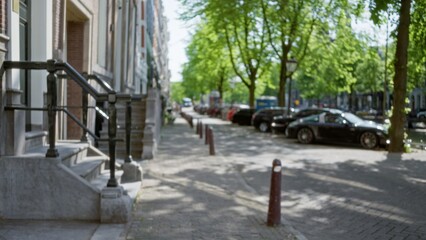 Blurred view of a quiet european street lined with parked cars and shaded by trees, capturing the essence of an urban cityscape with bokeh effect and natural serenity.