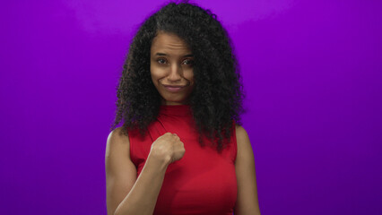 Young hispanic woman in red top points finger to chest against an isolated purple studio wall;...