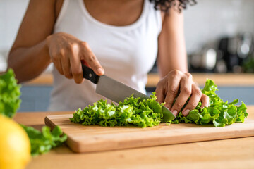 Woman Slicing Fresh Lettuce on Wooden Cutting Board in Kitchen
