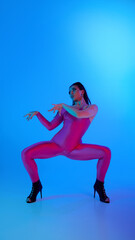 Performer wearing pink suit showcases jazz funk in brightly lit blue neon background. Concept of...