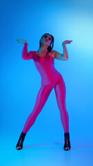 Dancer in vibrant pink bodysuit poses dynamically with blue neon light. Concept of aggressive...