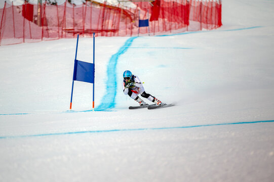 alpine ski racing downhill on snowy ski slope passing blue gate
