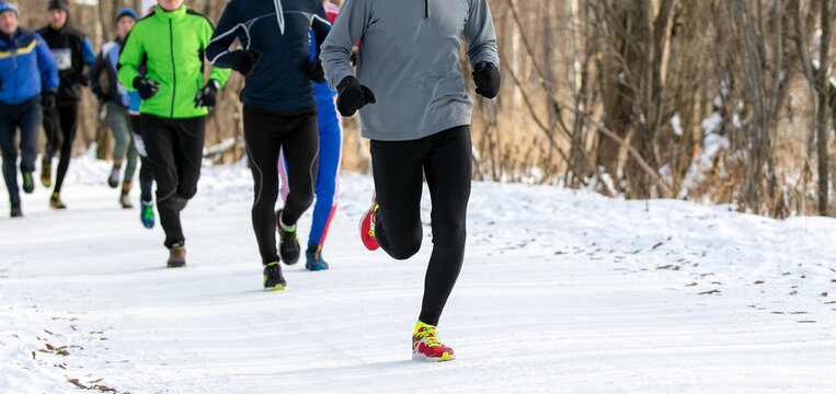 group runners athletes in winter race or marathon on snow-covered trail