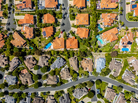 Symmetrical top-down drone shot of red-roofed homes with pools and palm trees in a planned neighborhood of Rancho Palos Verdes, California, featuring luxury architecture and green landscaping
