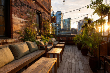 Urban rooftop terrace with string lights, weathered wood seating, potted plants and brick walls, golden hour cityscape visible in distance