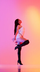 Woman performing in high heels against vibrant orange pink backdrop. Concept of fashion-forward...