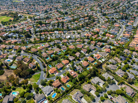 Aerial image of a tranquil suburban area in Palos Verdes, California, featuring curving roads, green parks, and homes with private swimming pools nestled in lush residential blocks

