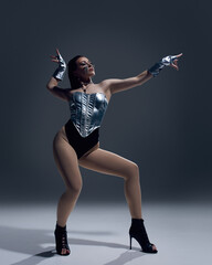 Jazz funk dancer in high heels striking dynamic pose against dark background. Concept of dance...