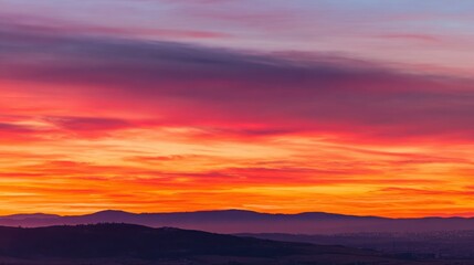 Dramatic sunrise with gradient orange and purple clouds, creating a panoramic abstract sky view.