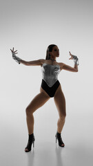 Elegant dancer striking dynamic pose in high heels against plain background. Concept of elite dance...