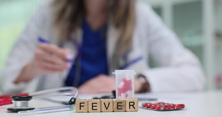 Fever word on wooden cubes stands against doctor by thermometer and red blister pack. Tools suggest temperature check and medication during sickness - Powered by Adobe