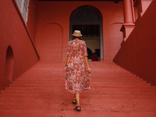 Young woman in ethnic dress and hat exploring the vibrant streets of Malacca, Malaysia. A blend of...