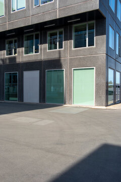 Contemporary facade with textured concrete and mint doors under harsh sunlight, representing urban design principles and copy space potential for commercial or branding use