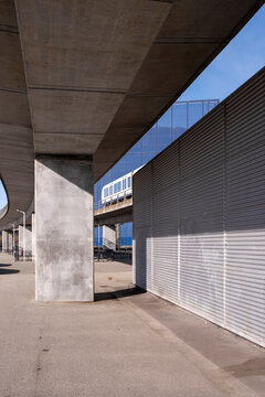 Underpass walkway with bold concrete pillars and lateral metal panels, creating a linear rhythm and offering clean copy space for infrastructure, transport and urban style topics