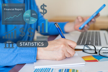Businesswoman analyzing financial statistics, kpi data, and performance indicators on a laptop and smartphone, evaluating project progress, sales, and company objectives, writing notes on a notepad