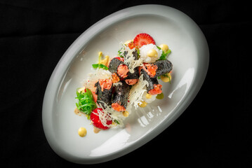 Gourmet sushi rolls with salmon roe, shredded topping, and seaweed garnish, served on rice and white plate against black background. High-end Japanese cuisine presentation.