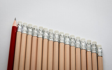 Red Pencil Standing Out Among Beige Pencils on White Background