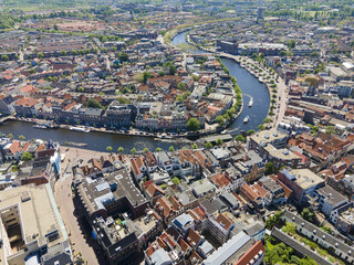 Aerial view of the winding river cutting through the city's heart, reflecting the sky, with buildings clustered along the banks, Amsterdam, North Holland, Netherlands.