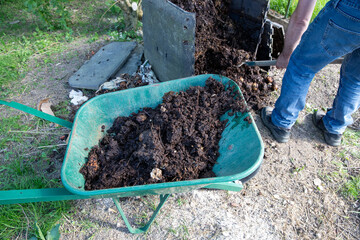 Homme avec une fourche creusant un bac à compost de jardin extérieur rempli de déchets alimentaires. Promouvoir le recyclage durable et les pratiques de compostage domestique.
